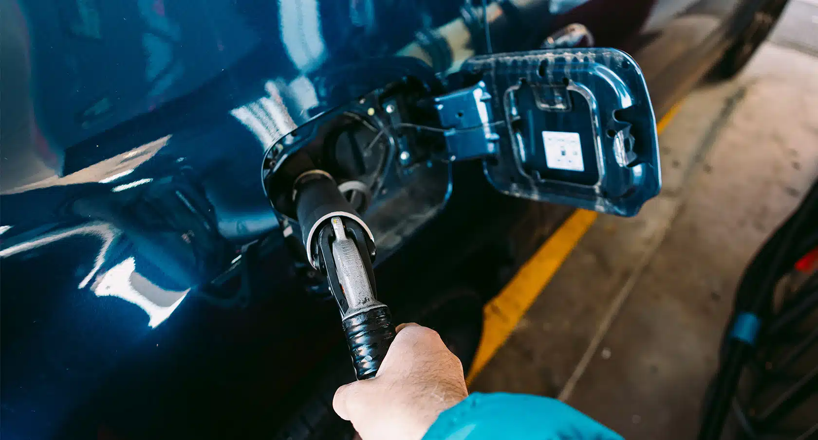 Eine Hand führt den Einfüllstutzen einer Gasanlage in den Tank eines Autos