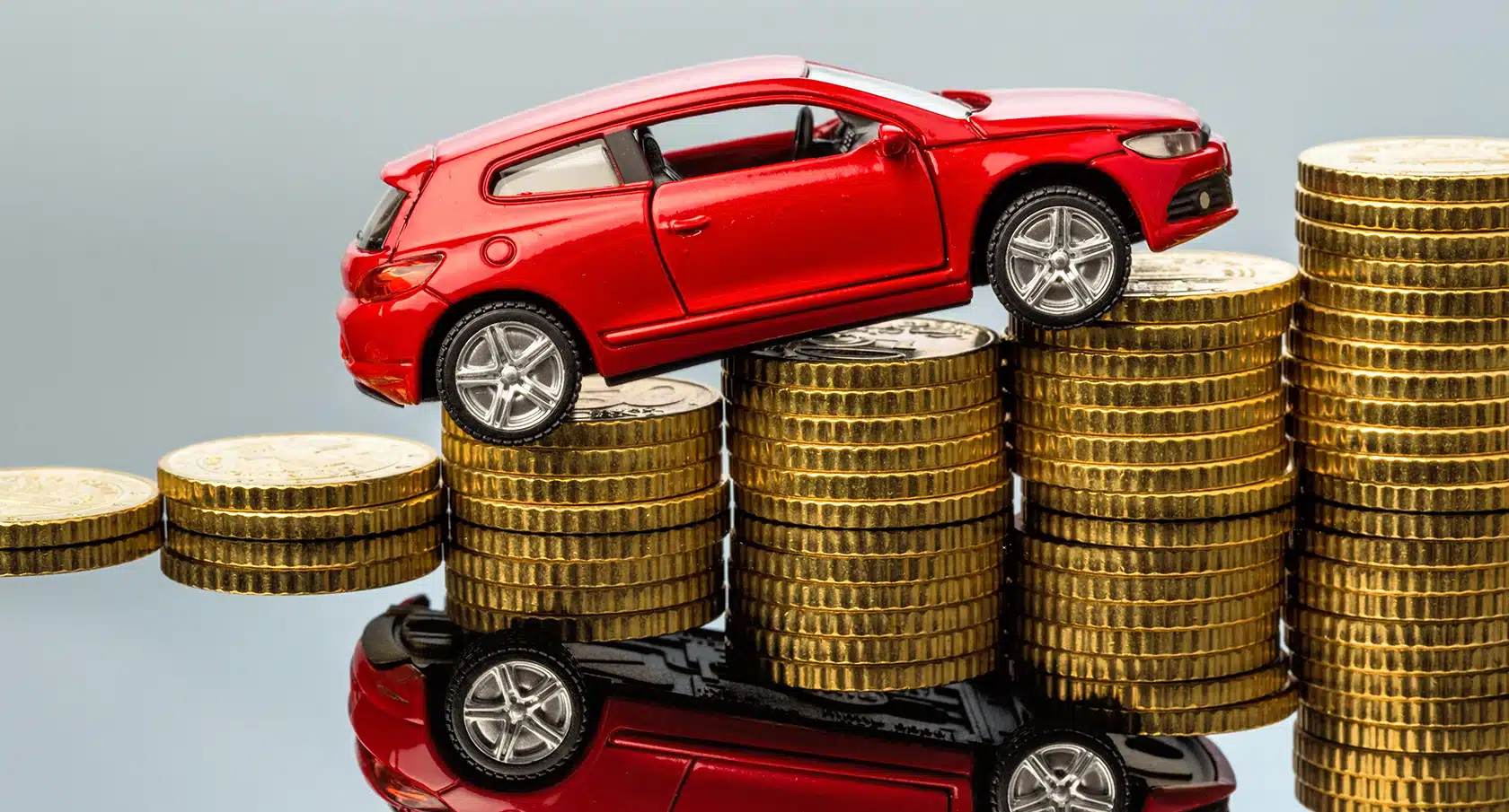 Rotes Spielzeugauto auf einem Stapel Münzen