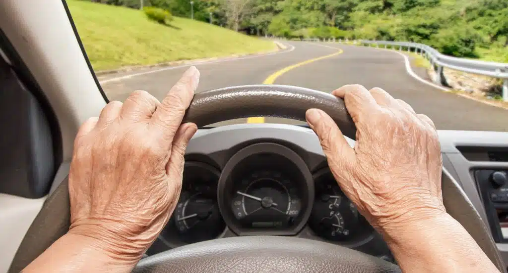 Faltige Hände am Lenkrad eines Autos