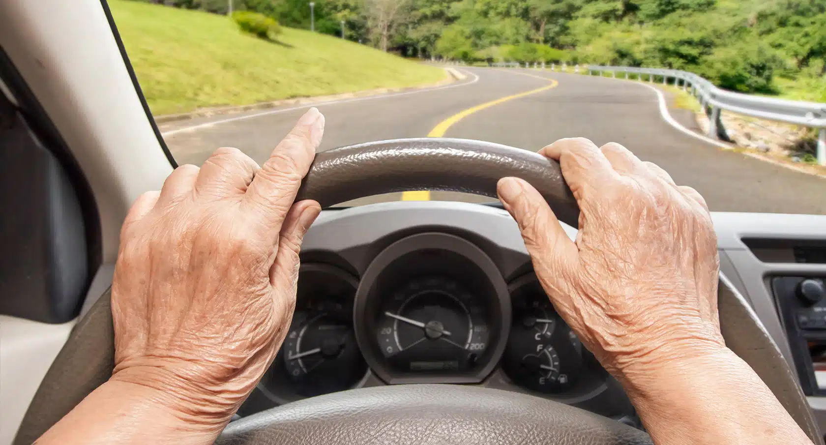 Faltige Hände am Lenkrad eines Autos
