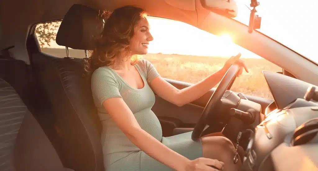 Eine schwangere Frau sitzt in einem Auto am Steuer