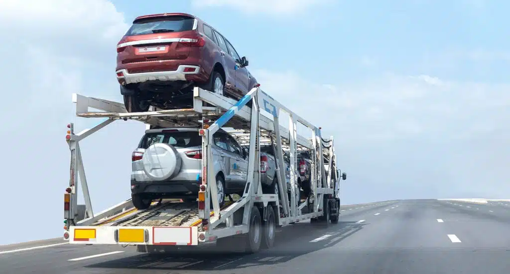 Ein mit Autos beladener Transporter fährt auf einer Straße