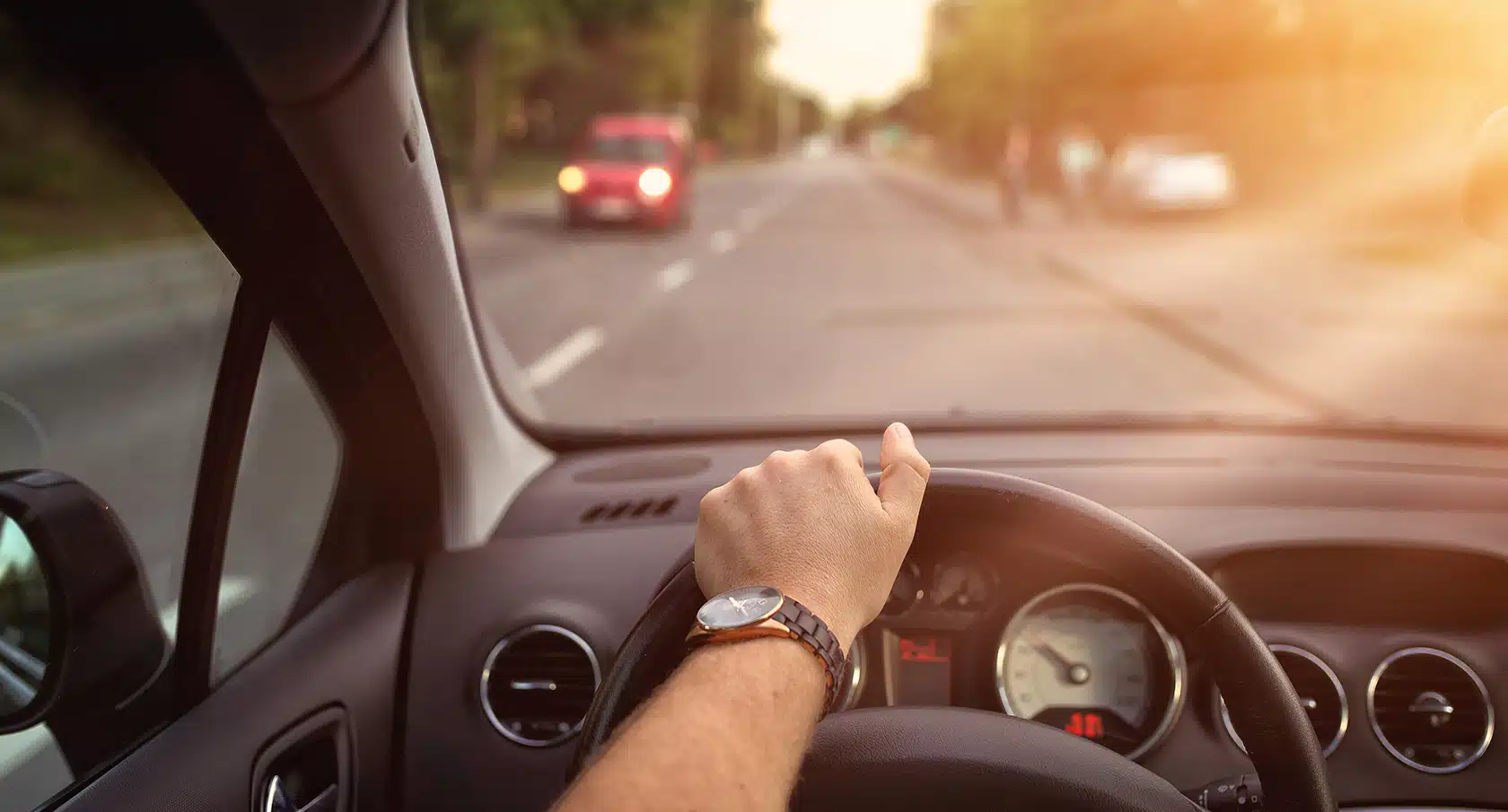 Eine Hand am Steuer eines Autos vor einer beschlagenen Scheibe