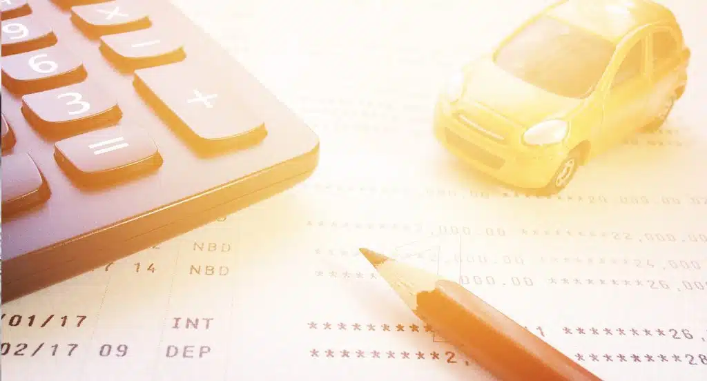 Taschenrechner, Bleistift und Spielzeugauto liegen auf einem Schreibtisch