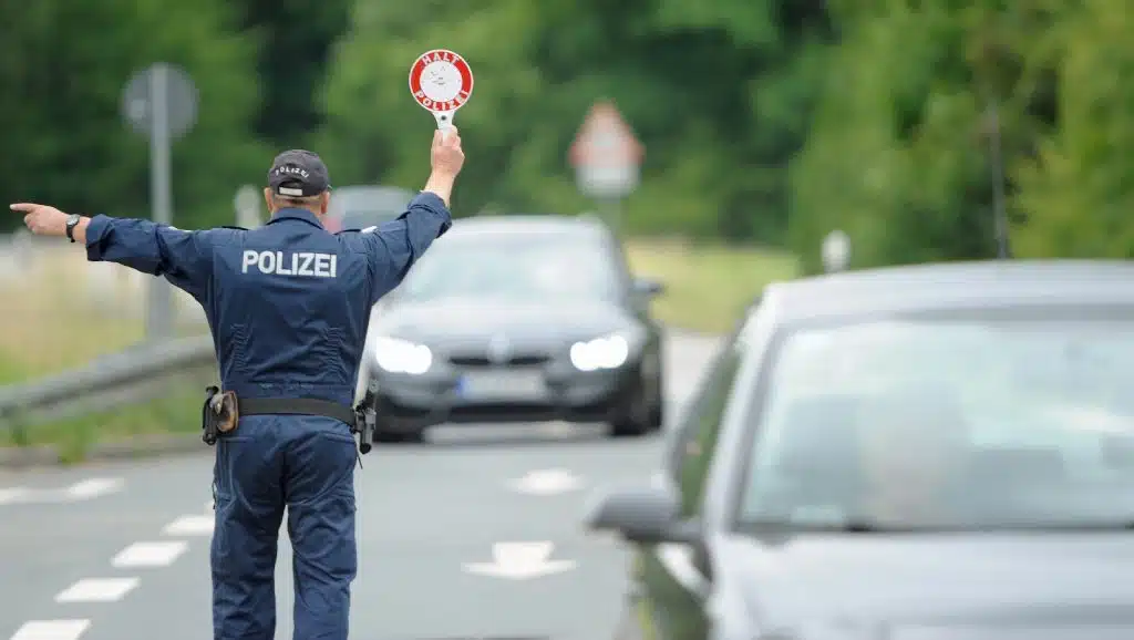 Polizist mit Anhaltestab signalisiert einem Auto an Rand zu fahren.