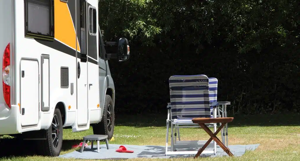 Campingstuhl steht vor einem Wohnmobil im Grünen