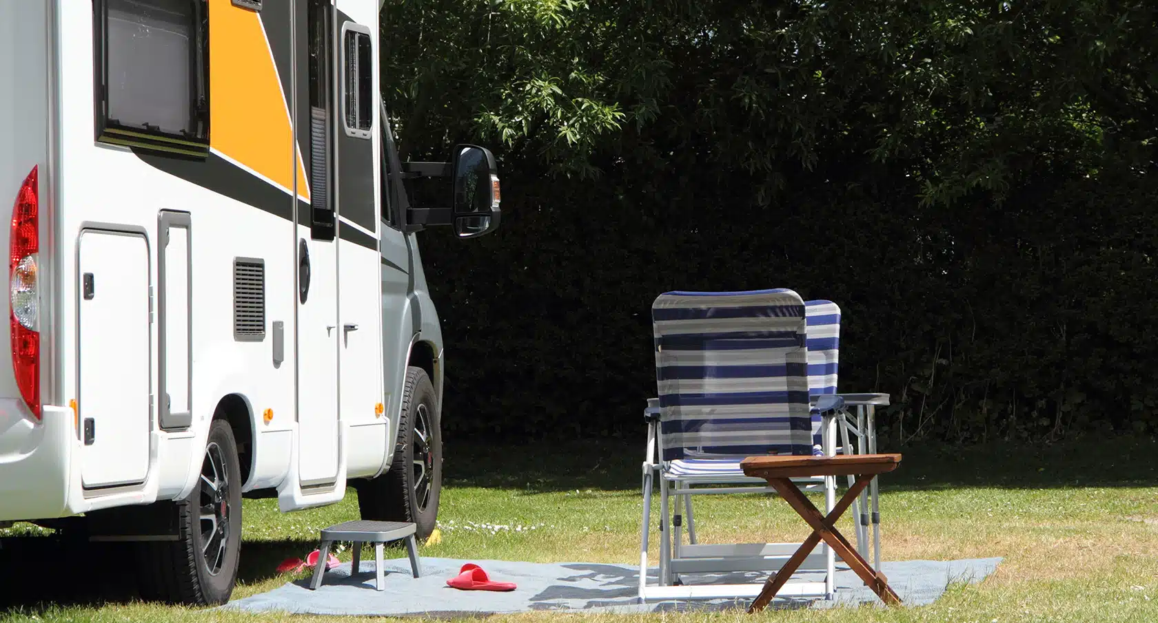 Campingstuhl steht vor einem Wohnmobil im Grünen