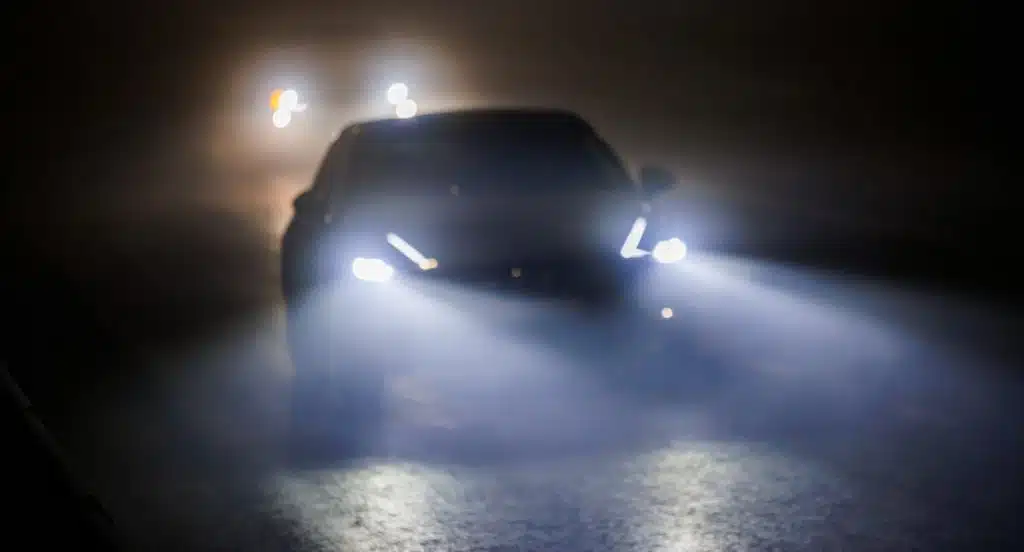Auto mit hellen Scheinwerfern fährt durch die Dunkelheit