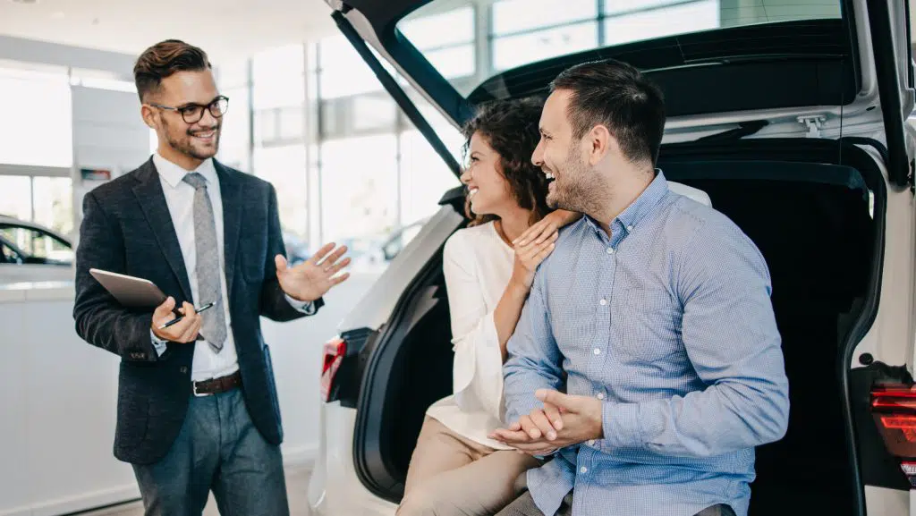 Fahrzeugwechsel: Ein Paar mittleren Alters wählt im Autohaus einen Pkw aus und lässt sich von einem Autoverkäufer beraten.