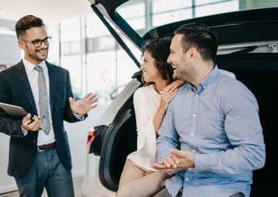 Fahrzeugwechsel: Ein Paar mittleren Alters wählt im Autohaus einen Pkw aus und lässt sich von einem Autoverkäufer beraten.