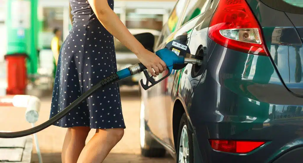 Eine Frau führt den Stutzen in den Tank eines Autos ein