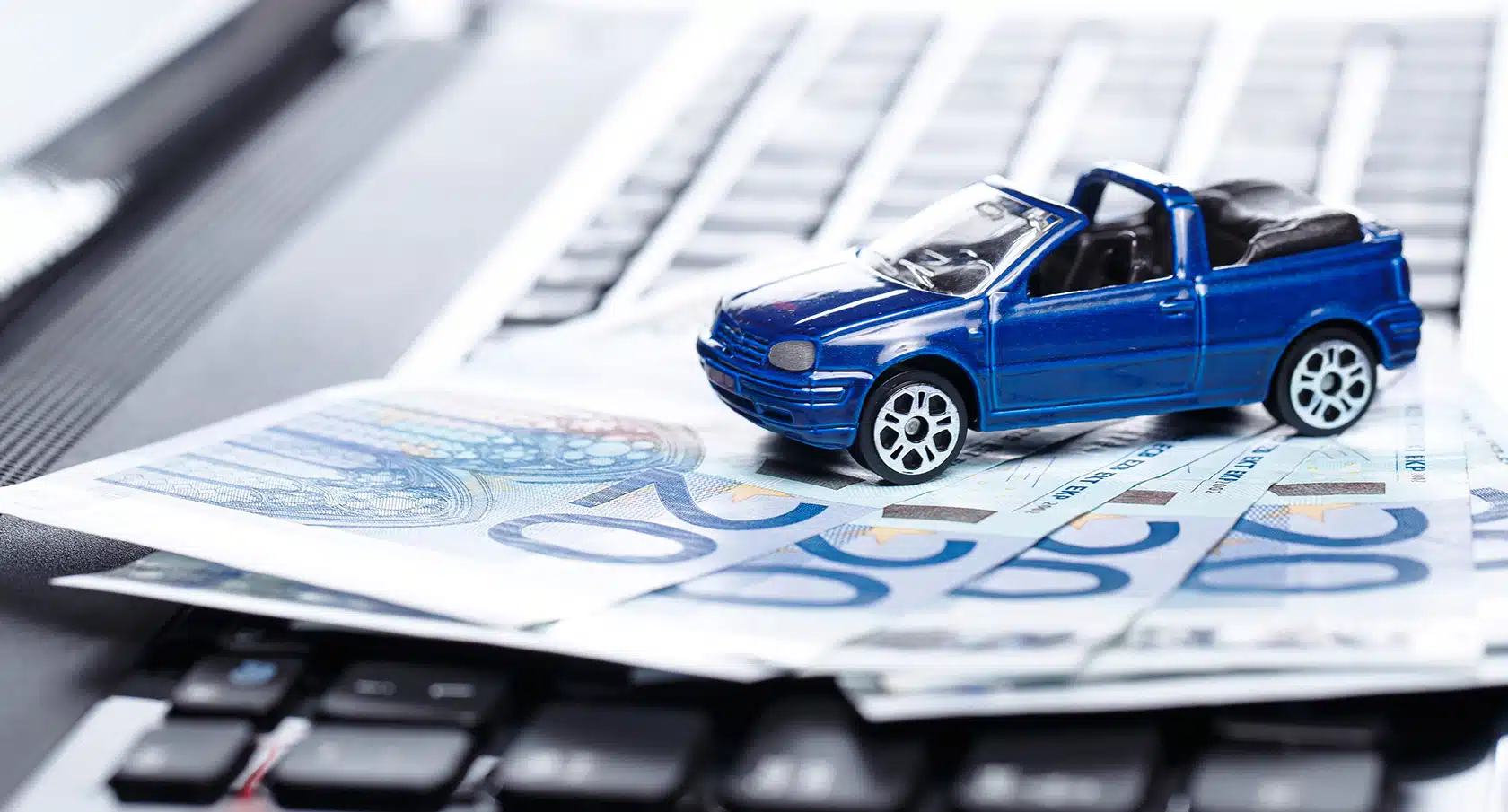 Kleines blaues Spielzeugauto steht auf einem Stapel Geldscheine
