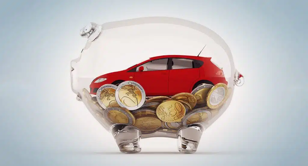 Spielzeugauto und Münzen im Inneren eines gläsernen Sparschweins