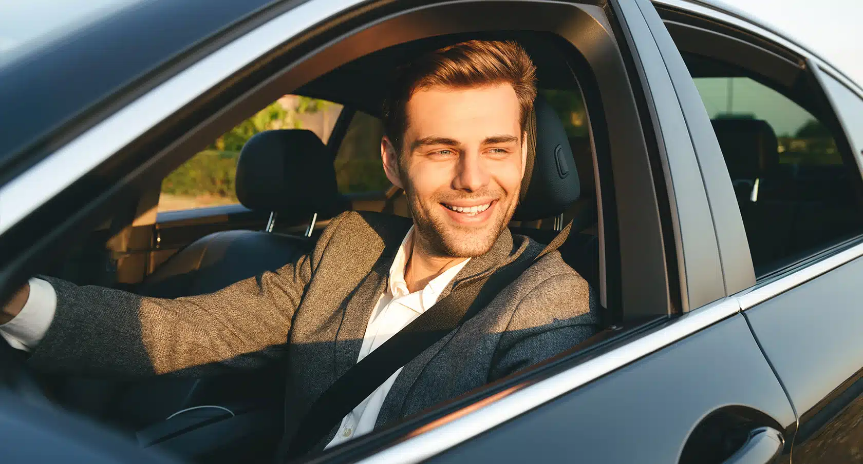 Lächelnder junger Mann schaut aus dem Autofenster eines Firmenwagens