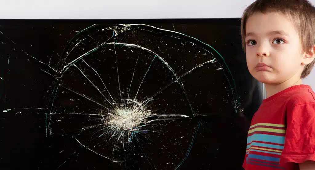 Kleines Kind steht vor einem TV-Gerät mit einem Sprung im Display