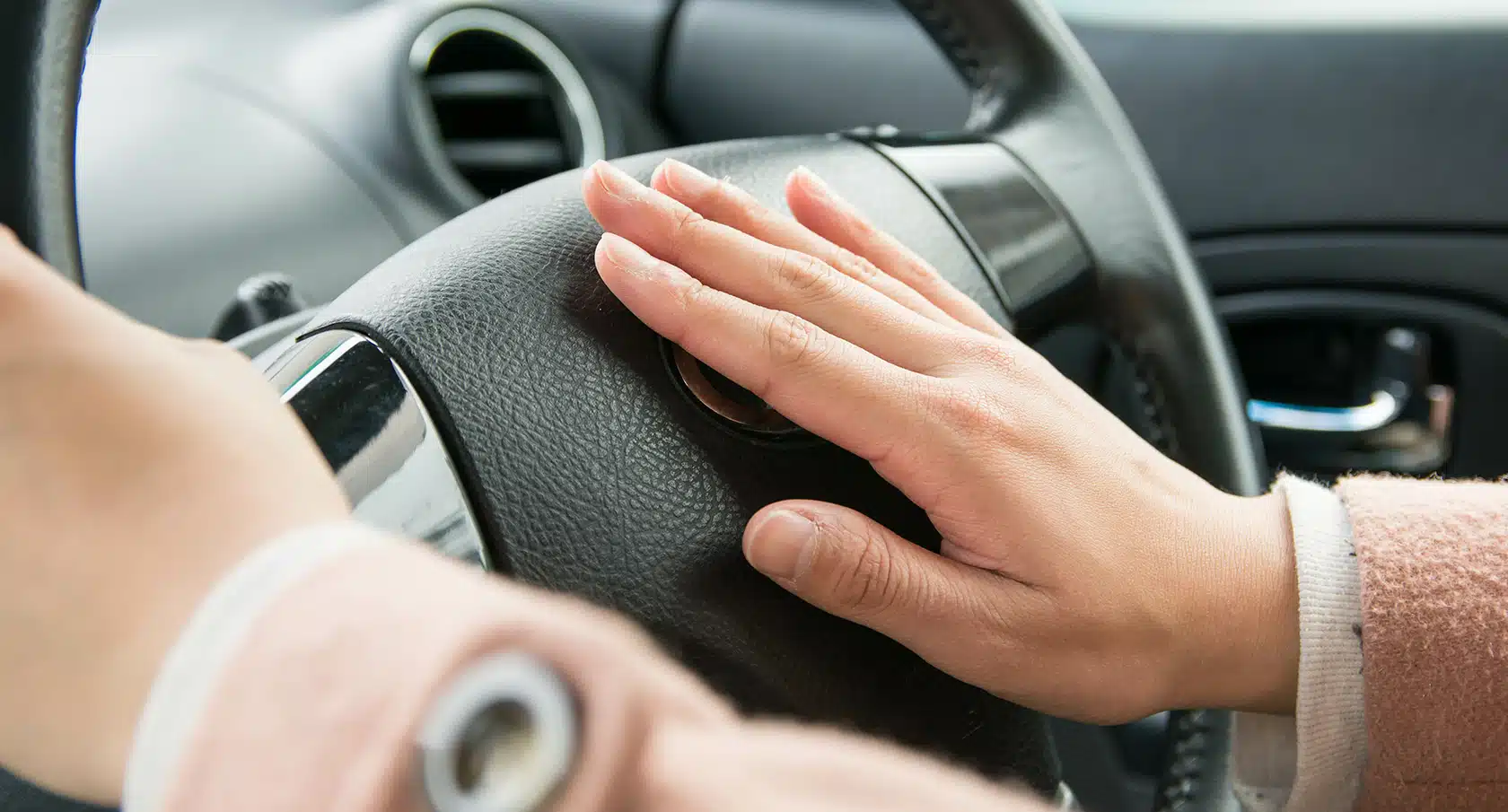 Eine Hand drückt die Hupe auf dem Lenkrad eines Autos