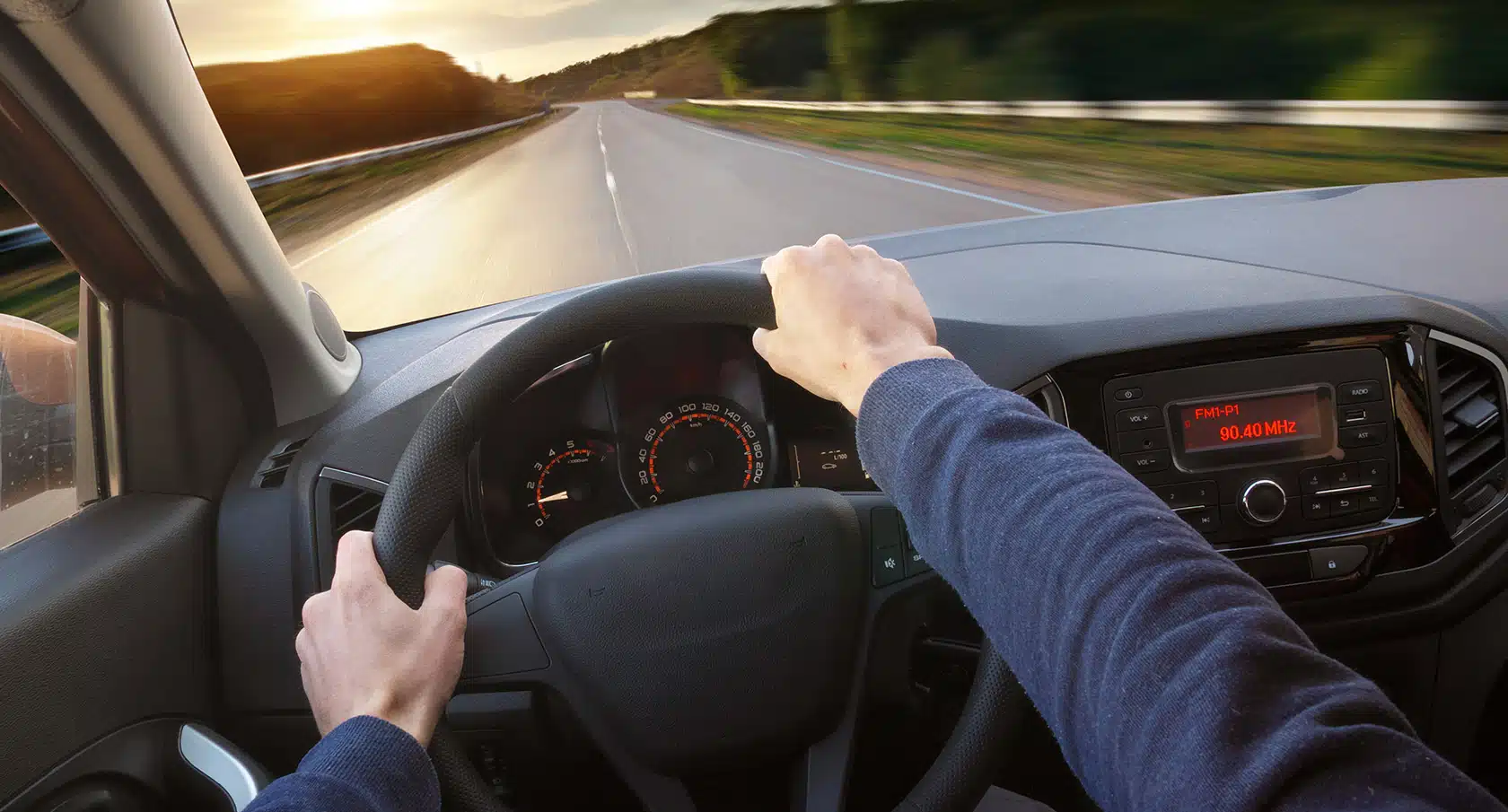Zwei Hände Am Lenkrad vor der Aussicht durch eine Autoscheibe auf die Straße
