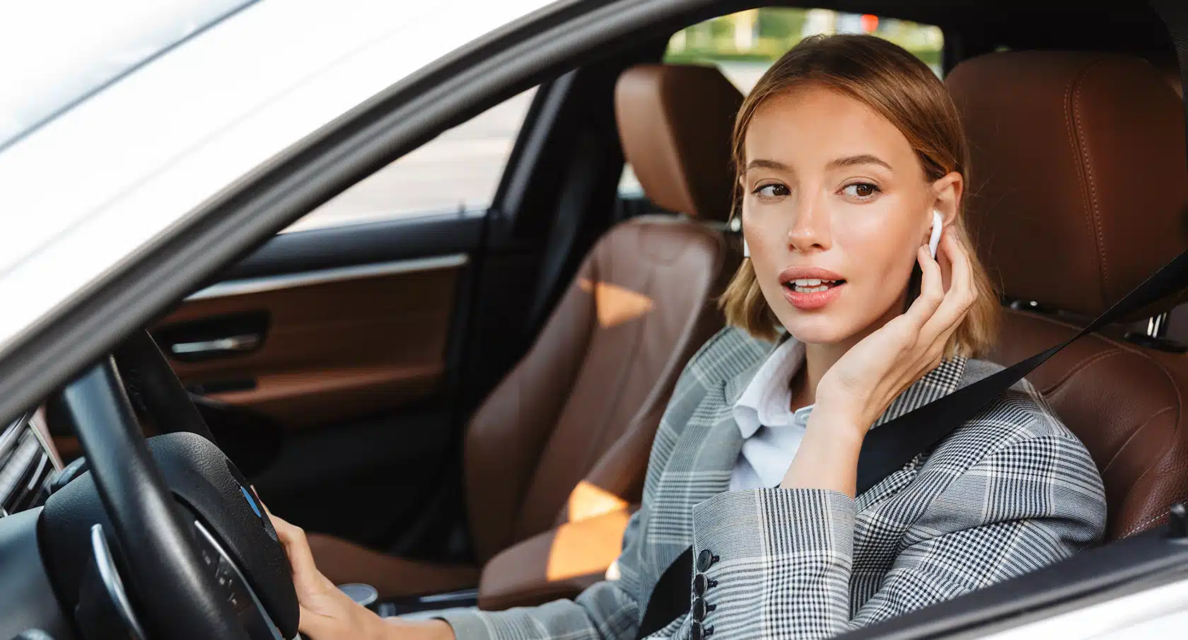 Junge Frau mit Kopfhörern am Steuer eines Autos