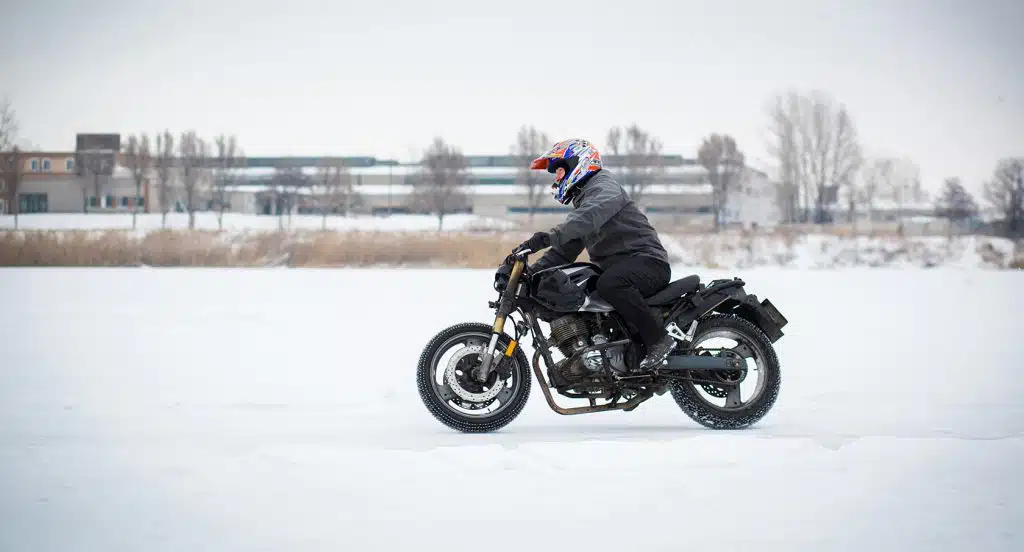 Motorradfahrer auf einer Maschine fährt durch eine Schneelandschaft