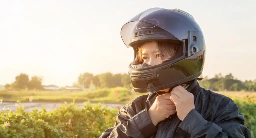 Junge Frau befestigt den Motorradhelm an ihrem Kinn