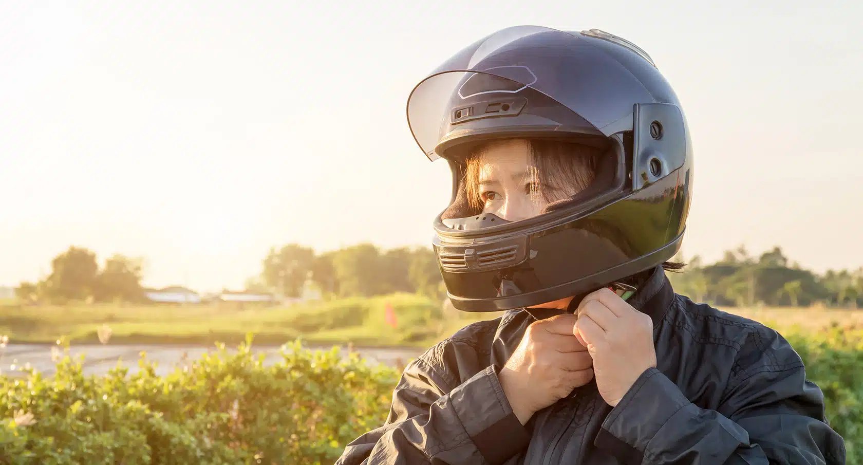 Junge Frau befestigt den Motorradhelm an ihrem Kinn