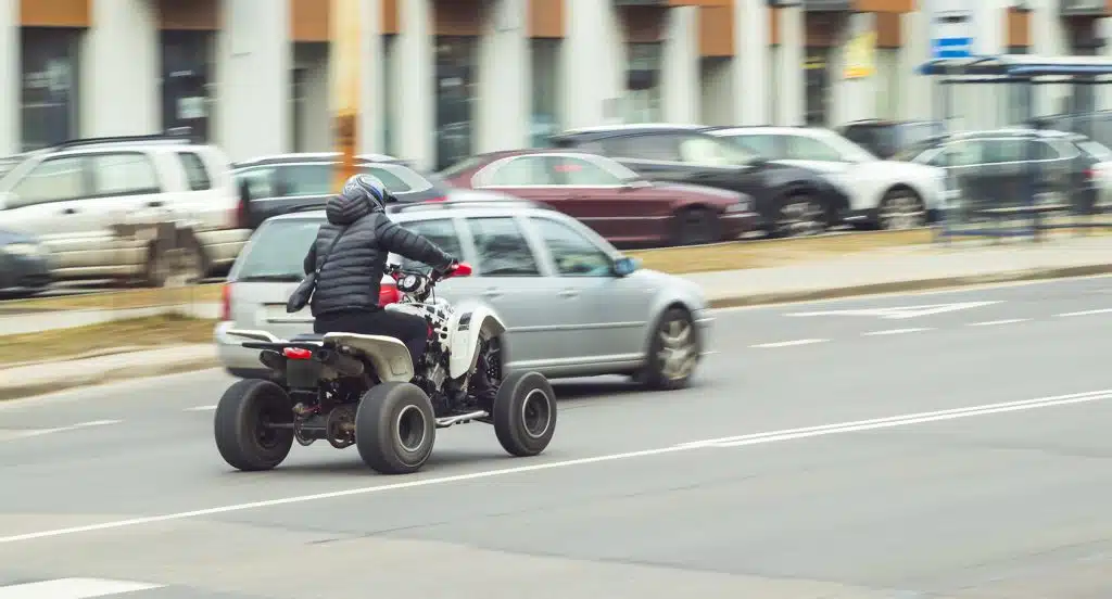 Ein Quad fährt auf einer Straße neben einem Auto