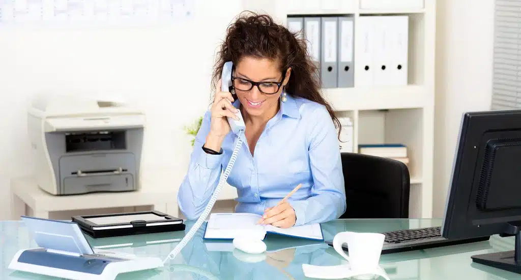 Junge Frau sitzt am Schreibtisch in einem Büro und telefoniert