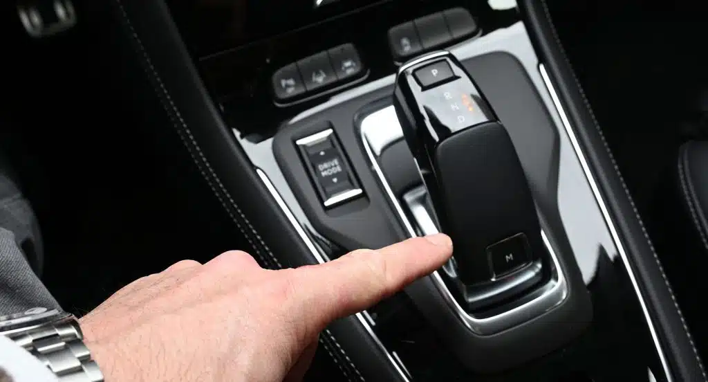 Zeigefinger zeigt auf eine Automatikschaltung im Auto