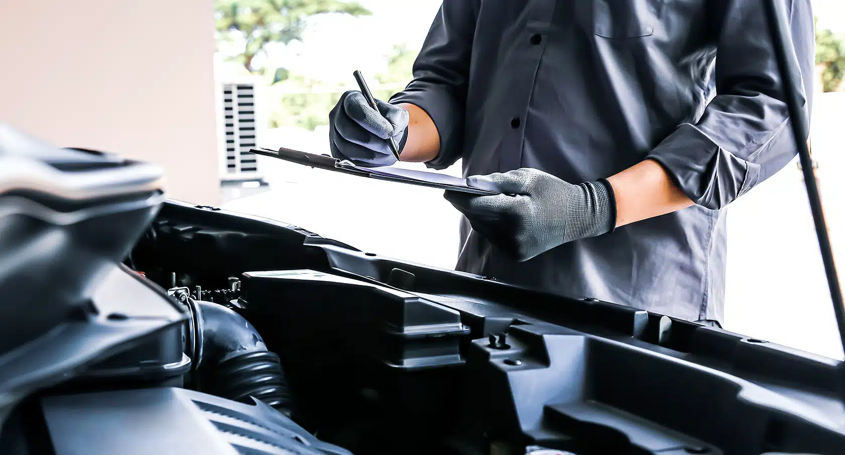 Mechaniker trägt etwas in das Scheckheft eines Autos ein