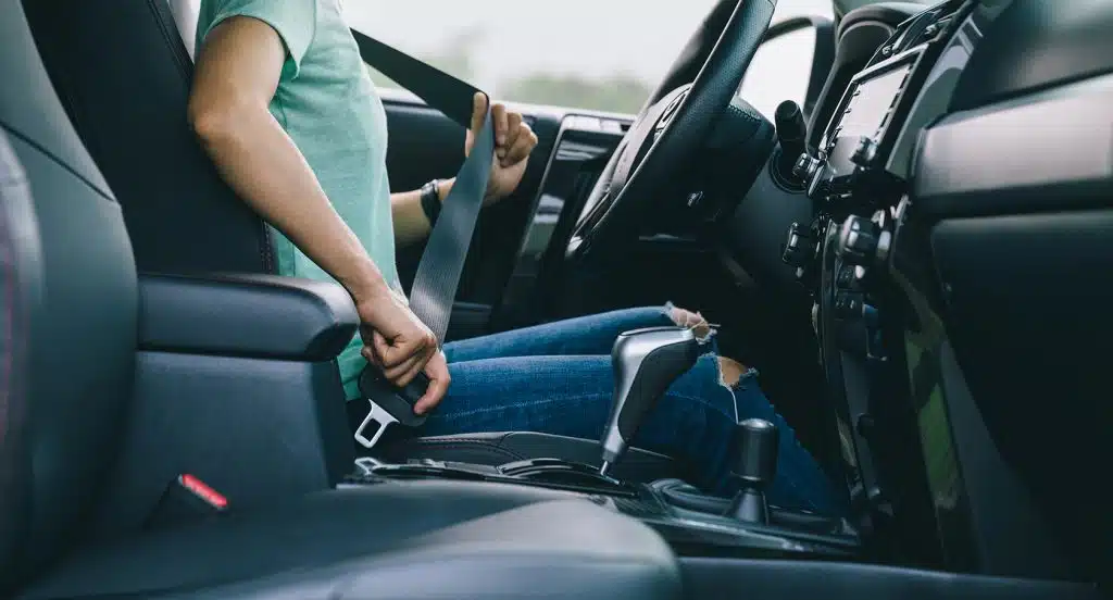 Frau auf dem Fahrersitz eines Autos schnallt sich an