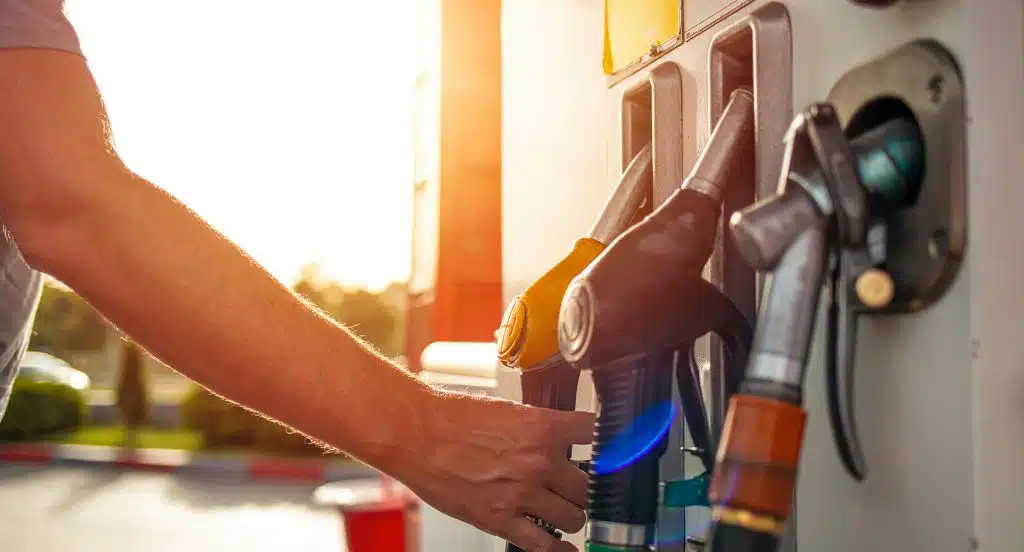 Eine Hand greift nach einem Zapfhahn an der Tankstelle