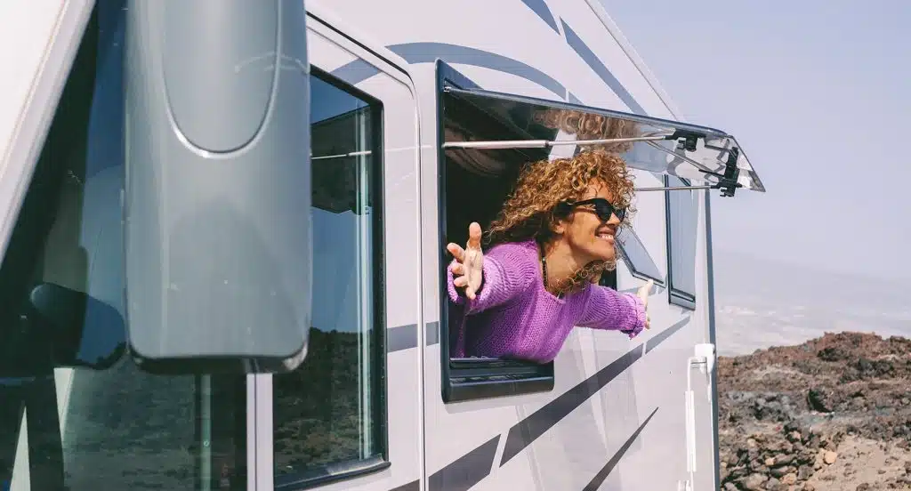 Junge Frau schaut aus dem Fenster eines Tiny Houses heraus