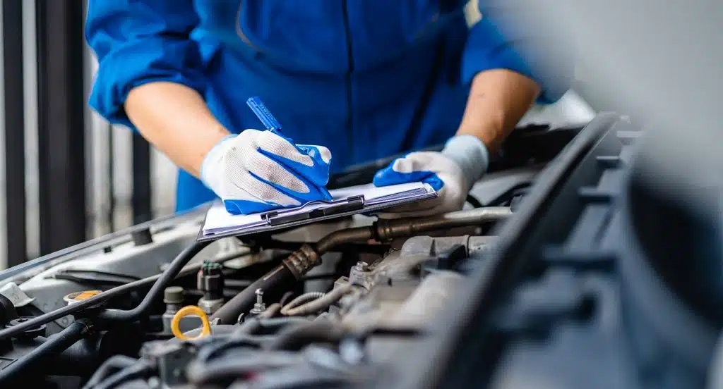 Geöffneter Motorraum eines Autos wird von einem Mechaniker gewartet