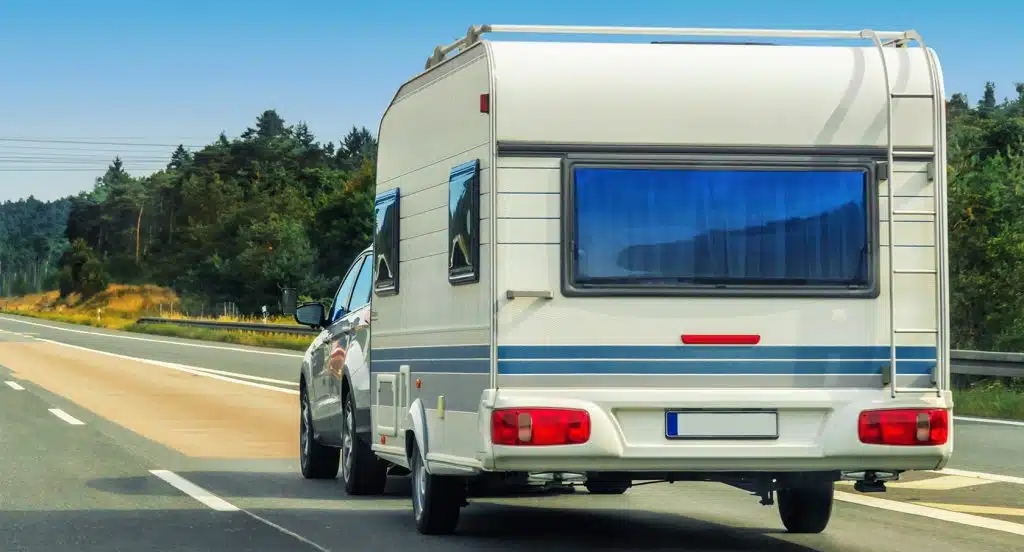 Auto mit Wohnwagen fährt auf einer Landstraße