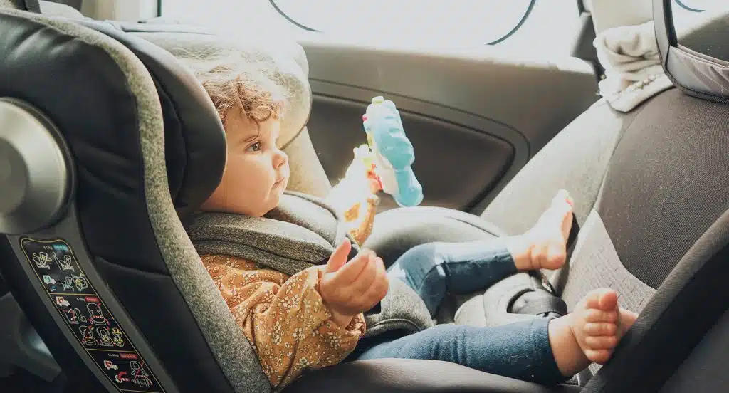 In einem Auto eingesperrtes Kleinkind sitzt im Kindersitz