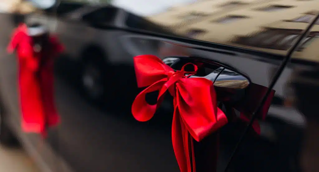 Rote Schleife ist um den Türgriff eines schwarzen Autos gewickelt