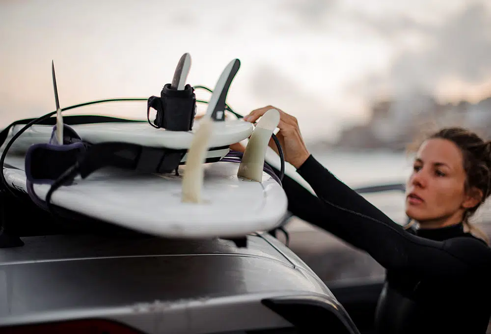 autogadget_dachgepaecktraeger Eine Person schnallt zwei Surfboards auf das Dach eines Autos