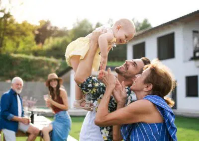 Familie spielt mit kleinem Baby vor eigenem Haus