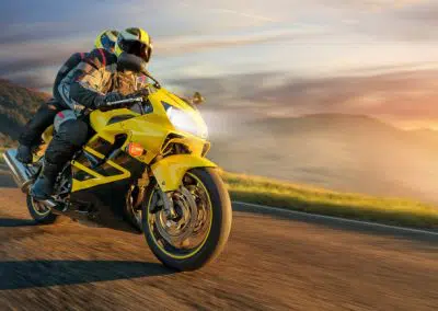 Gelbes Motorrad mit Fahrer und Beifahrer