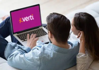 Ein Paar sitzt auf dem Sofa am Laptop, auf dem das Verti Logo zu sehen ist