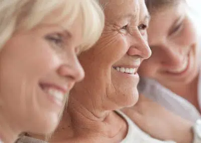 Drei Generationen von Frauen lehnen lachend die Köpfe zusammen