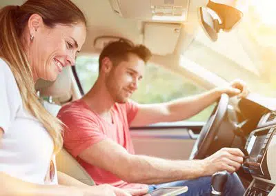 Pärchen sitzt bei Sonnenschein im Auto