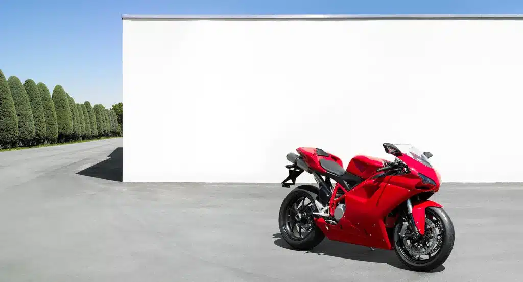 Rotes Motorrad steht vor einer weißen Wand