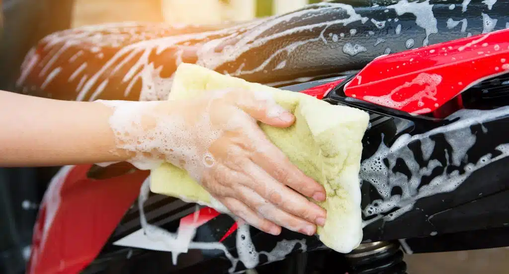 Eine Hand schäumt ein Motorrad mit einem Lederlappen ein