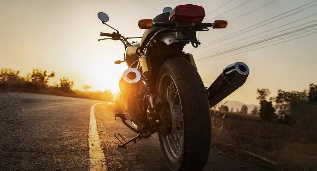 Ein abgestelltes Motorrad steht in der Abendsonne an einer Straße