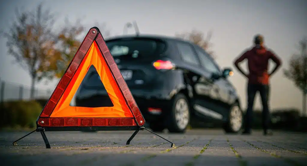 Ein Warndreieck steht vor einem Auto auf der Straße