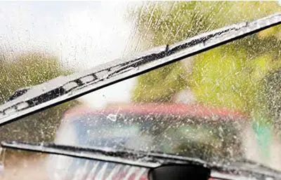 Regen auf Autoscheibe und zwei wischende Scheibenwischer