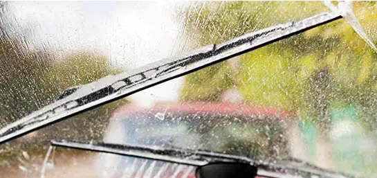 Regen auf Autoscheibe und zwei wischende Scheibenwischer