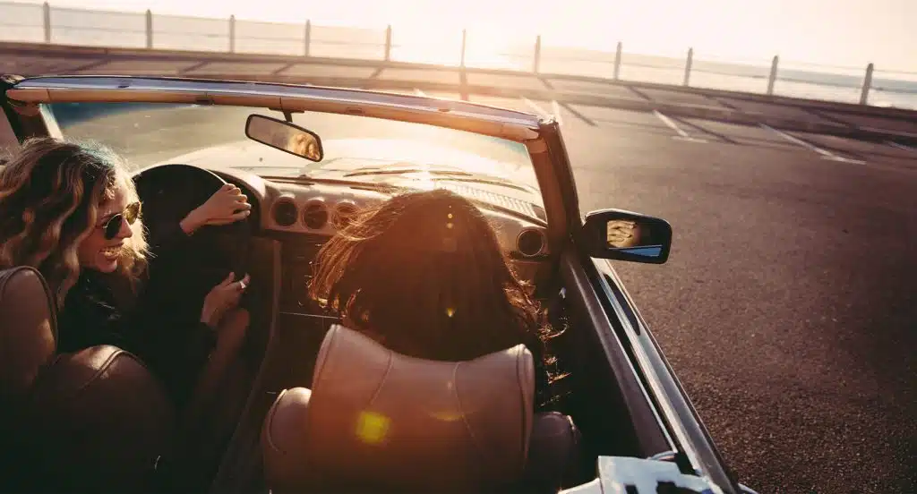 Zwei Autofahrer fahren dem Sonnenuntergang im offenen Cabrio entgegen