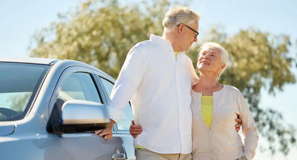 Seniorenpärchen steht vor einem Auto